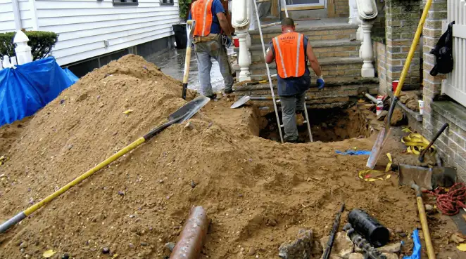 Contractors performing foundation protection and exterior drainage excavation near residential home steps in Baltimore, MD